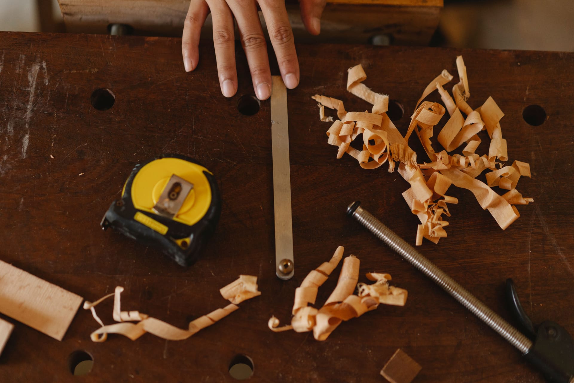 Manos trabajando madera con herramientas de taller